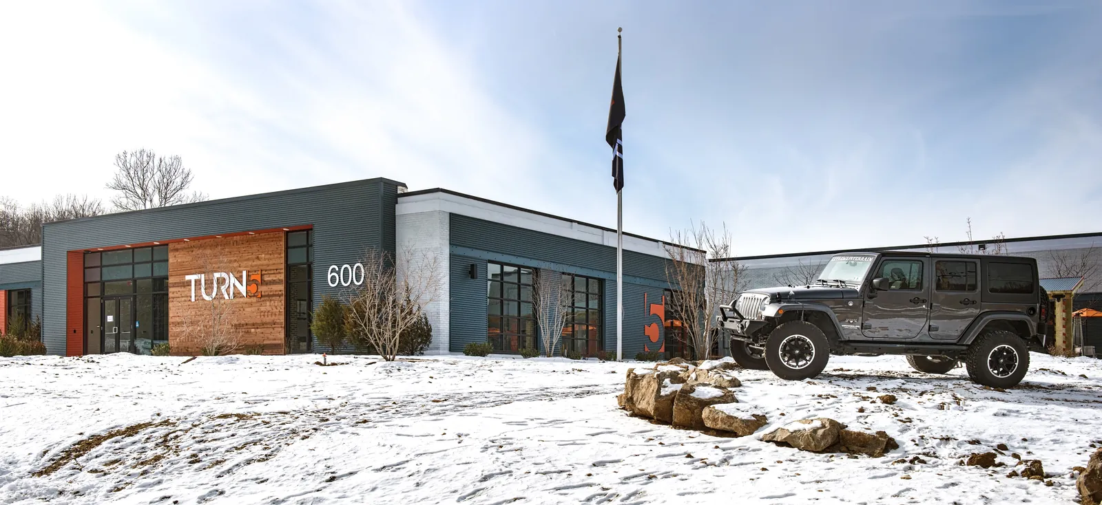 Turn5 headquarters entrance with a wood-clad sign, the number 600 and a Jeep parked in the snow