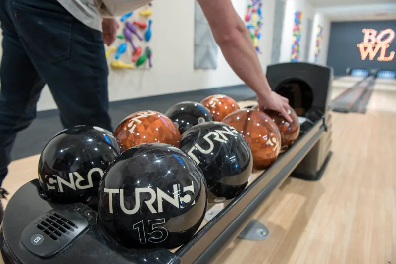 Bowling balls branded with the Turn5 logo on the ball return