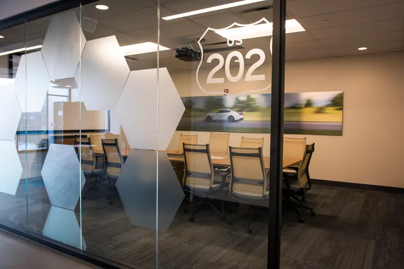 Glass-walled conference room with a US 202 route shield and frosted hexagon film