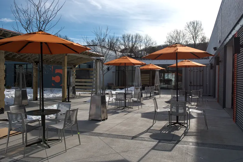 Courtyard patio with orange umbrellas, patio heaters and metal tables