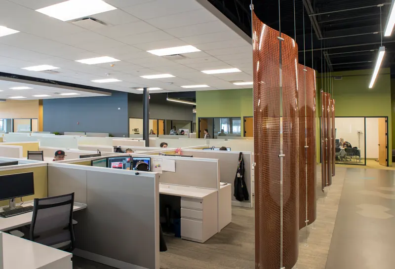 Open office floor with a hanging copper-toned perforated screen
