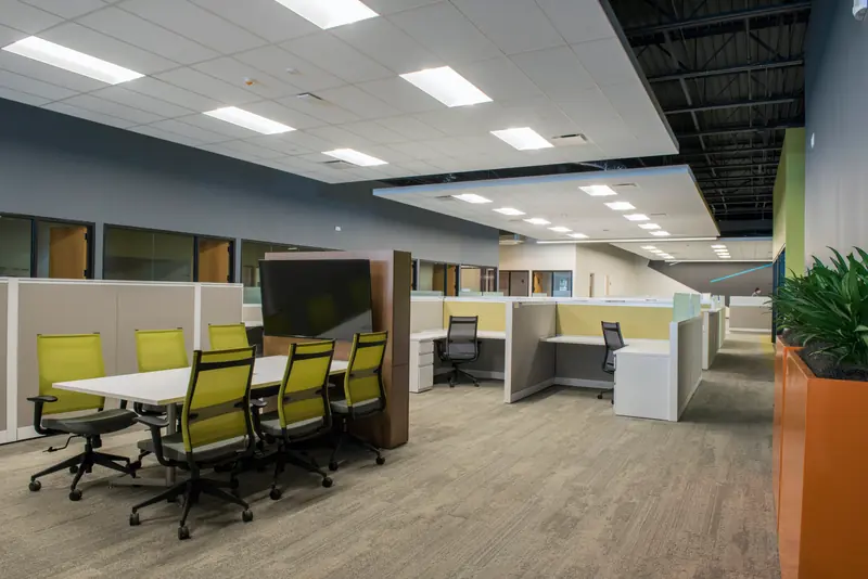 Open office with a small meeting table and green chairs
