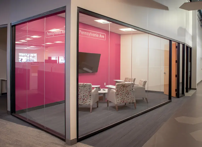 Glass-walled huddle room with a pink wall labeled Pennsylvania Ave