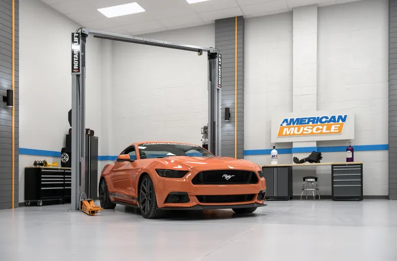 Studio bay with an orange muscle car on a lift and an American Muscle sign