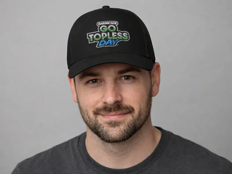 Black trucker cap with the Go Topless Day logo embroidered on the front