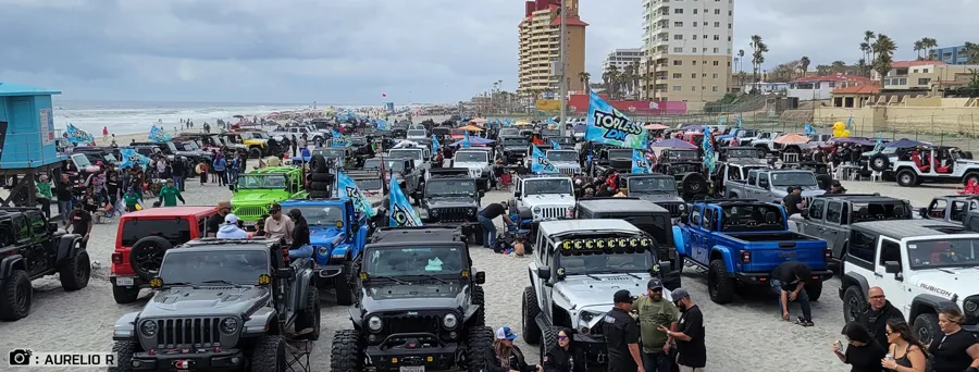 Crowd and Jeeps on the beach at a Go Topless Day event